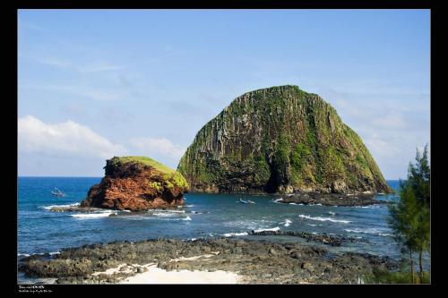 a large rock in the ocean next to the beach at Thy Hung legacy hotel in Tuy Hoa