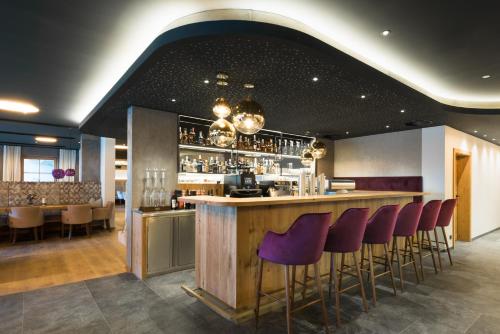 un bar con sgabelli viola in un ristorante di Boutiquehotel die Alpbacherin ad Alpbach