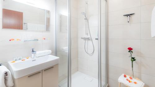 een witte badkamer met een douche en een wastafel bij Strandhotel Klopeinersee in Sankt Kanzian