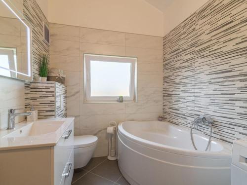 a bathroom with a tub and a toilet and a sink at House Toni for 8 persons in Briševo