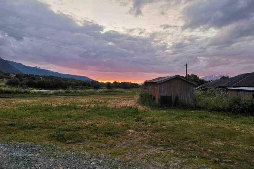 an old barn in a field with the sunset in the background at In the heart of the Lyngen alps, Holmen i Lyngen in Lyngseidet