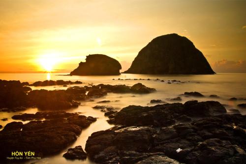 a sunset over the ocean with rocks in the water at Thy Hung legacy hotel in Tuy Hoa