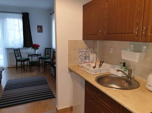 a kitchen with a sink and a dining room at Relax Apartman Veresegyház in Veresegyház