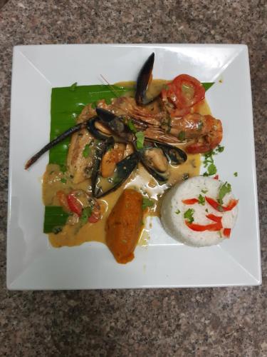 a plate of food with seafood and vegetables on a table at La Rose du Bresil Marie-Galante in Capesterre-de-Marie-Galante