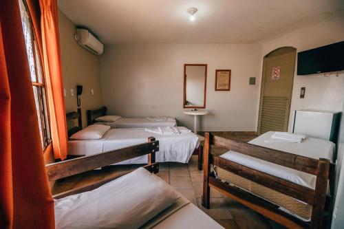 a room with three beds and a mirror at Hotel Triângulo in Caldas Novas