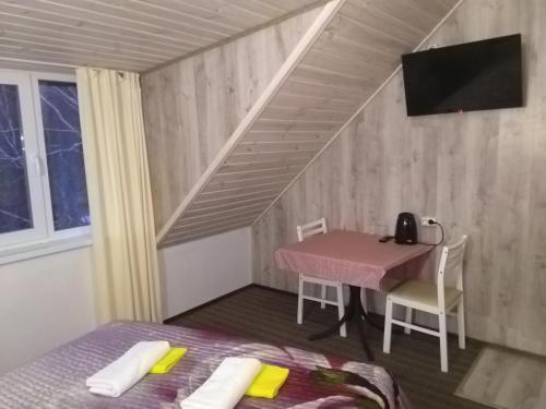 a room with a bed, chair, table and window at Mini Hotel Oliva in Svyatogorsk