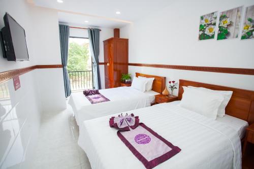 two beds in a hotel room with white sheets at Thy Hung legacy hotel in Tuy Hoa