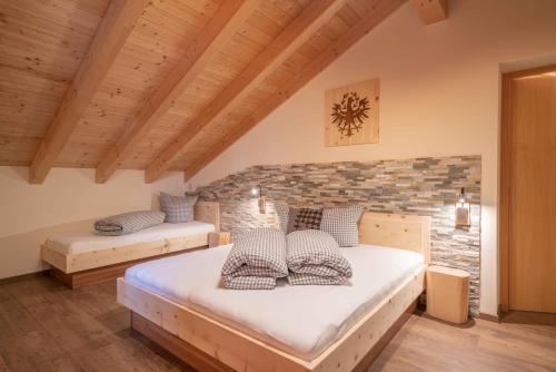2 camas en una habitación con una pared de ladrillo en Landhaus Kalvarienberg en Ladis