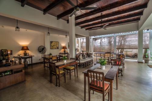 a dining room with tables and chairs and windows at Sayura House in Colombo