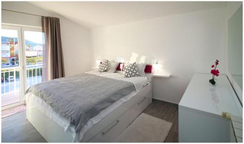 a white bedroom with a bed and a window at Mikelin in Primošten