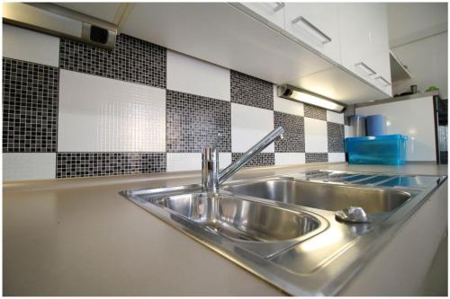 a stainless steel sink in a kitchen with black and white tiles at Mikelin in Primošten