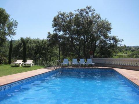 a large blue swimming pool with chairs and trees at CASA LA GRANJA in Olvan