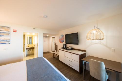 a bedroom with a bed and a desk with a television at SeaCrest Oceanfront Hotel in Pismo Beach
