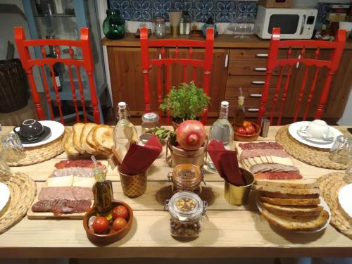 a table with food and bread and bottles and red chairs at Les Magranes Bed & Breakfast in Argelaguer