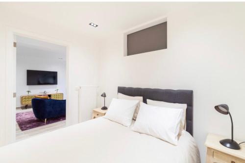 a bedroom with a white bed and a blue chair at COZY APARTMENT IN BRUSSELS in Brussels