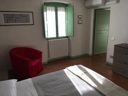 a bedroom with a bed and a red chair at Appartamento Il Glicine in Pistoia