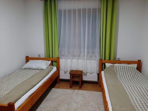two beds in a room with green curtains and a window at privatni smestaj Dobri in Bujanovac
