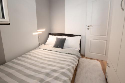 ein kleines Schlafzimmer mit einem Bett mit einer gestreiften Matratze in der Unterkunft Apartman Slavica in Rijeka