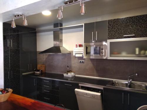 a kitchen with a sink and a microwave at Casa Rural Ruralba in Alba de los Cardaños