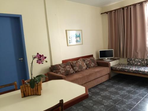 a living room with a couch and a tv at Residencial Praia Mar in Florianópolis