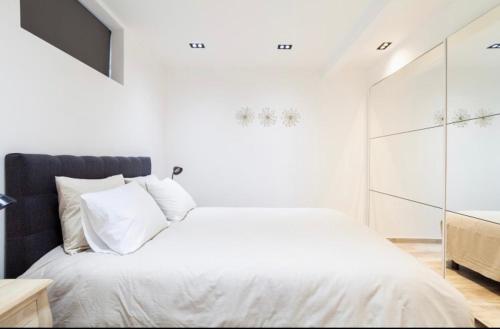 a white bed with white pillows in a bedroom at COZY APARTMENT IN BRUSSELS in Brussels