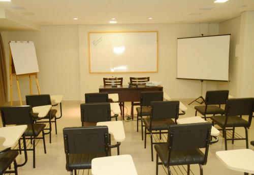 a classroom with desks and chairs and a whiteboard at Hotel Palace Santarém Brasil in Santarém