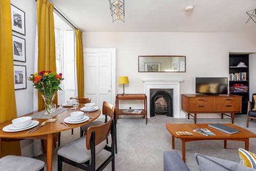 Una sala de estar con mesa y sillas y una chimenea. en Abbey View, en Bath