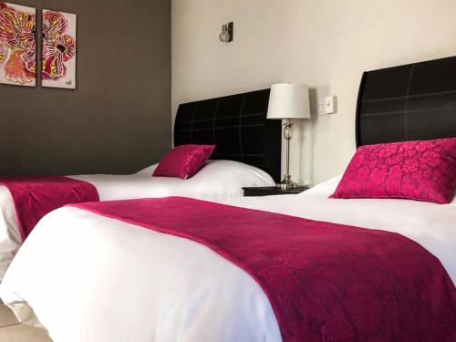 two beds in a hotel room with red sheets at Hotel Bugambilias Rooms in Tequisquiapan