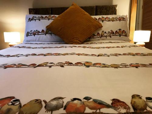 un letto con un mucchio di uccelli dipinti sopra di Clarabel's Guest House- The Nook a Wombourn