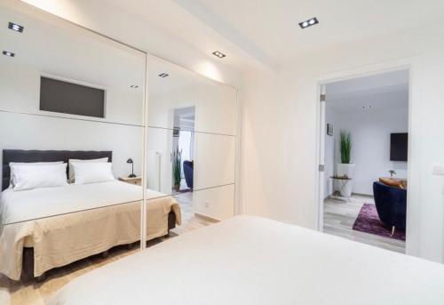 um quarto branco com 2 camas e um espelho em COZY APARTMENT IN BRUSSELS em Bruxelas