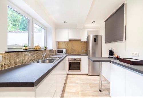 a kitchen with white cabinets and a stainless steel refrigerator at COZY APARTMENT IN BRUSSELS in Brussels
