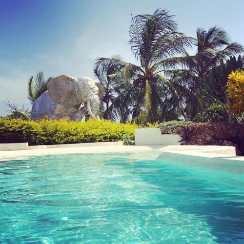 a swimming pool with an elephant statue in the background at Fortamu Twiga-House in Watamu