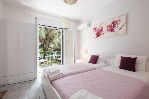two beds in a white room with a window at Eftyxia apartments in Paleokastritsa