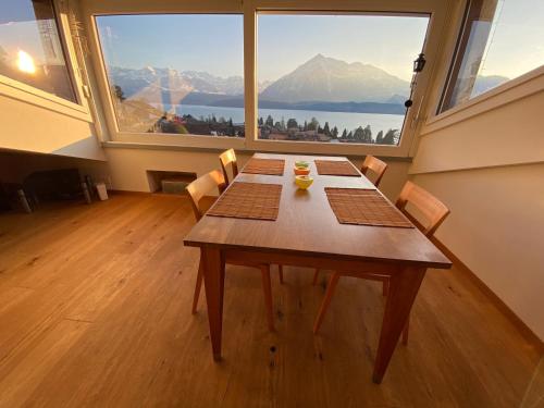 a dining room with a table and a large window at Otium-Oberhofen in Oberhofen am Thunersee