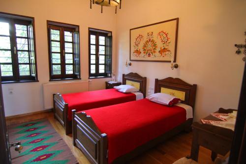 two beds in a room with red sheets at Mansion Viglatoras in Áno Poróïa
