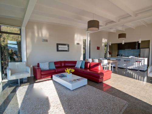 a living room with a red couch and a table at Kotare Point Paradise - Akaroa Holiday Home in Akaroa