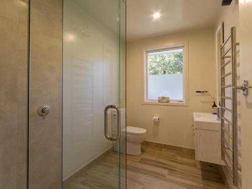 a bathroom with a shower and a toilet and a window at Alchemy Cottage - Arrowtown Holiday Home in Arrowtown