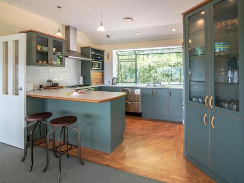a kitchen with blue cabinets and a island with bar stools at Rue Noyer Lookout - Akaroa Holiday Home in Akaroa