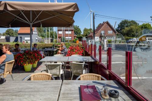 a table with an umbrella and people sitting at a restaurant at Vivaldi Hotel in Westerlo