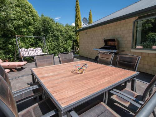 a wooden table and chairs on a patio with a grill at Rue Noyer Lookout - Akaroa Holiday Home in Akaroa