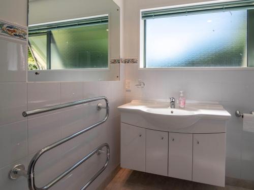 a white bathroom with a sink and a window at Rue Noyer Lookout - Akaroa Holiday Home in Akaroa