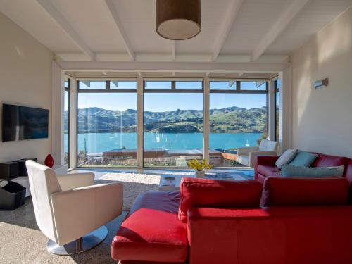 a living room with a red couch and a large window at Kotare Point Paradise - Akaroa Holiday Home in Akaroa