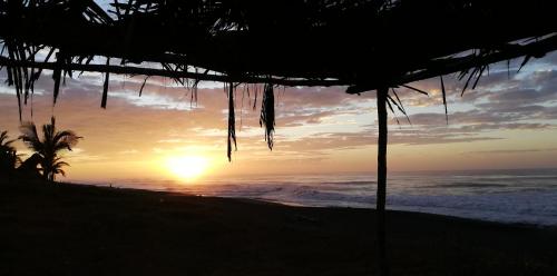 a sunset on the beach with a beach umbrella at Pacifico El Paredon in El Paredón Buena Vista