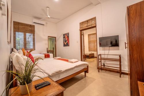sypialnia z łóżkiem, telewizorem i stołem w obiekcie Sayura House w Kolombo