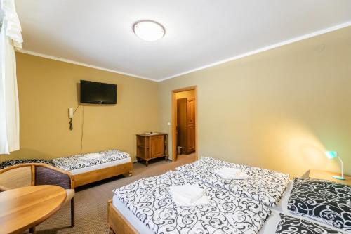 a room with two beds and a table and a tv at Hotel Perla Jizery in Josefuv dul