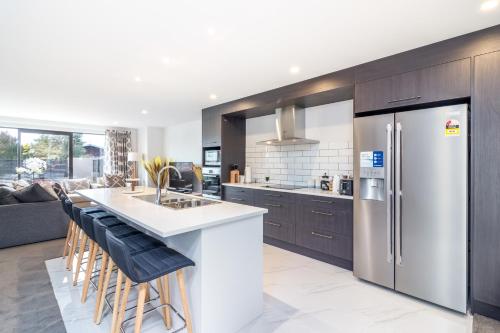a kitchen with a refrigerator and a counter with stools at Restful in Riccarton - Christchurch in Christchurch