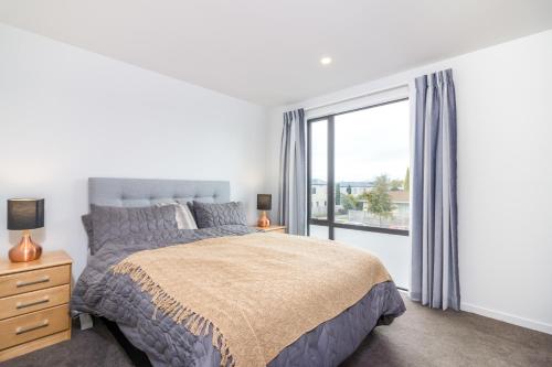 a bedroom with a bed and a large window at Restful in Riccarton - Christchurch in Christchurch