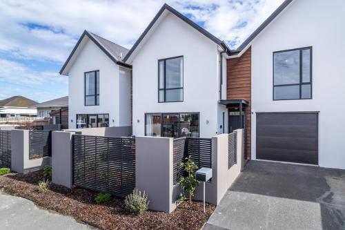 a white house with a black fence at Restful in Riccarton - Christchurch in Christchurch