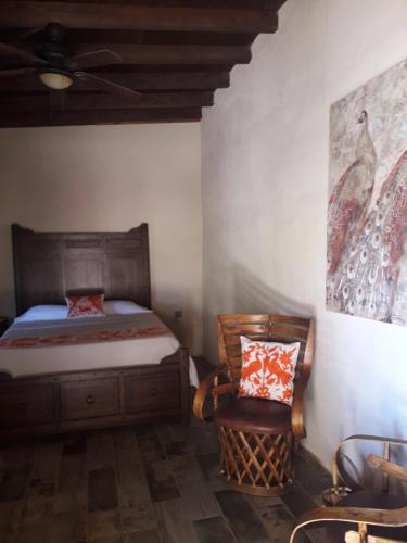 a bedroom with a bed and a chair and a painting at Rancho Espinoza in Paredones