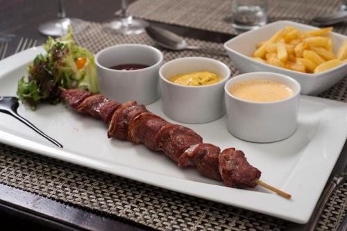 a plate of food with sausages and fries on a table at Hotel Golf de Pierpont in Bons Villers